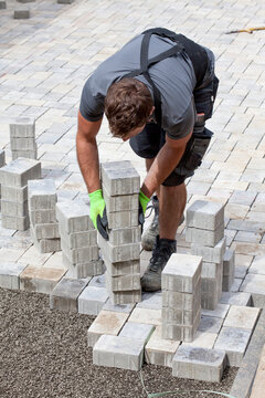 Germany, Rhineland Palatinate, Young man assembling paving stones