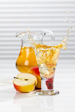 Glass of apple juice besides apples and pitcher