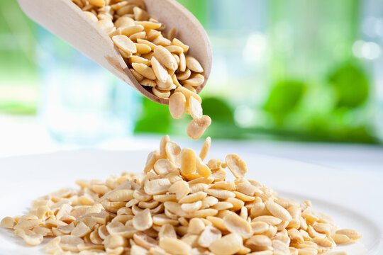 Soya beans pouring from wooden scoop, close up
