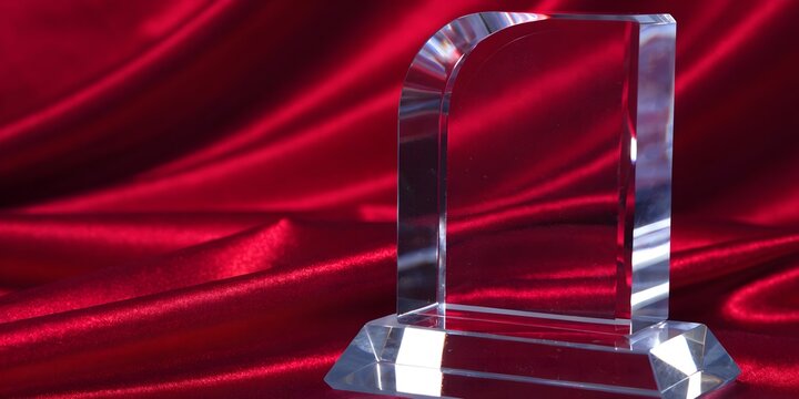 Clear acrylic award plaque on red satin background, elegant crystal trophy