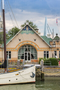 Historic clubhouse building behind a classic sailboat in Rotterdam, Netherlands