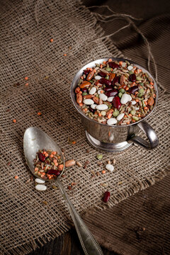 Minestrone mixture (mixed pulses and grain) in small white bowl and a spoon on jute fabric, close-up