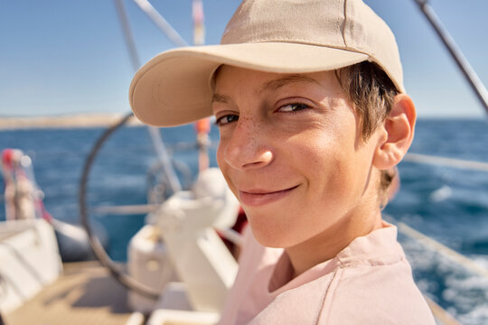 A smiling teenage boy enjoys sailing on the ocean in Croatia