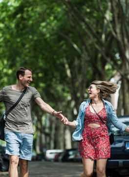 A happy man and woman run along a city street