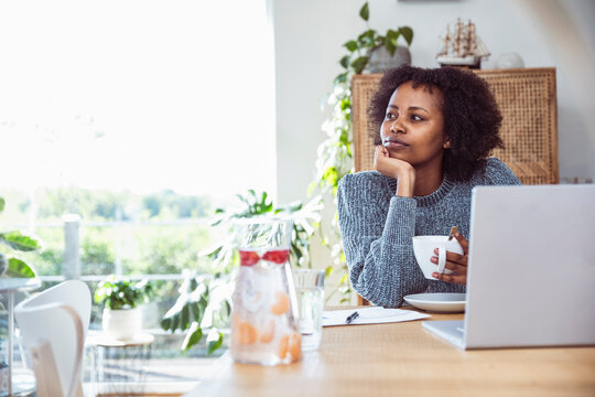 A woman looks out the window while working at her home office