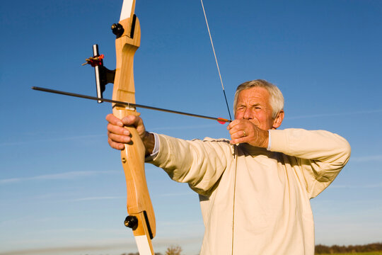 Senior adult man using bow and arrow