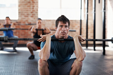 Fototapeta premium Fitness, class and man with barbell in gym, endurance or bodybuilding routine for muscle development. Health club, athlete and people with equipment for wellness, training and exercise with balance