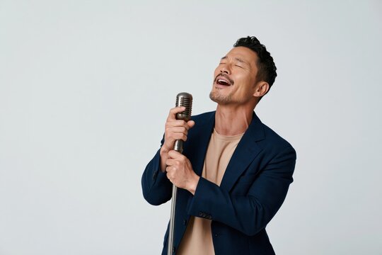 Solo male singer emoting with vintage microphone in simple studio setting wearing navy blazer for concert promo and poster background