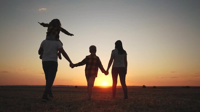 Silhouette of a family in a field at sunset. Family, silhouette, walking, park walking together, sunset. Family walking together at sunset. The photo is of a family walking in a lifestyle field at.