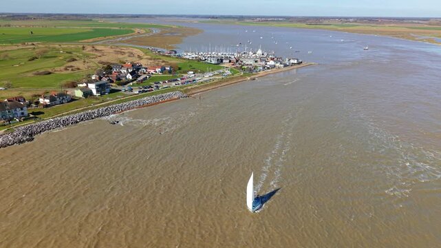High angle aerial view of a small private yacht sailing out of the estuary near Felixstowe Ferry