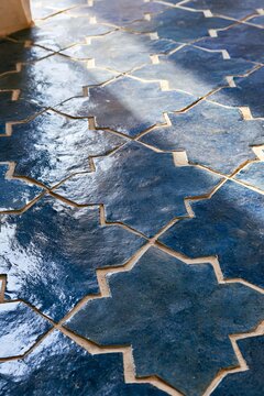 Closeup of hand-crafted indigo zellige tiles in a star-and-cross pattern, showcasing natural color variations in a Moroccan riad setting