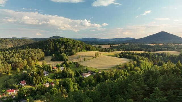 Aerial view of Czech countryside at sunset, village among forested hills and golden fields, Bohemian Switzerland