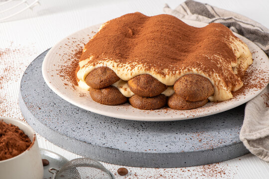 Homemade Tiramisu Cake Dusted with Cocoa Powder on a Ceramic Plate