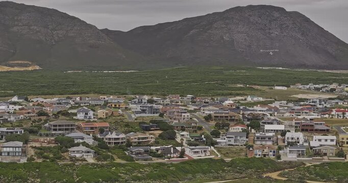 Gansbaai South Africa Aerial v4 telephoto flyover along Stanford's Cove shoreline, residential townscape and coastal mountain backdrop - Shot with Mavic 3 Pro Cine - Jan 7th 2024