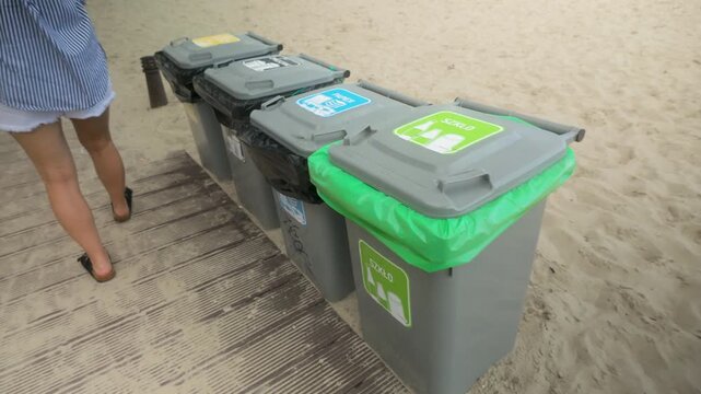 Close up of color coded recycling bins for paper plastic and mixed waste on a sandy beach. Concept for sustainability and eco friendly tourism.