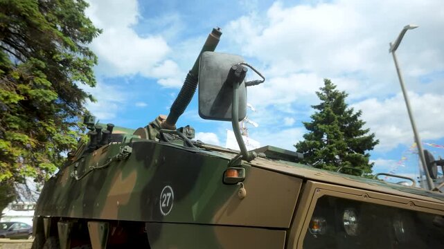 Close up of a camouflage military armored vehicle parked outdoors under a blue sky. Suitable for defense, security, and army technology content.
