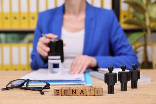 In a bright office filled with yellow folders, a person prepares important documents while tiny figures represent senators. This scene captures the essence of governance and decision-making.