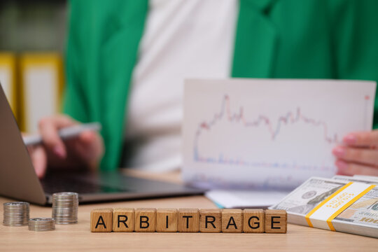 In a bright workspace, a person studies financial graphs while holding a document. On the table, stacks of coins and cash represent the world of trading.