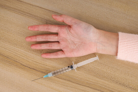 High Angle of Syringe Beside Open Palm