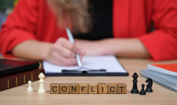 In a cozy office filled with greenery, a person writes notes while pondering on conflict resolution strategies using chess pieces to symbolize tactical moves.