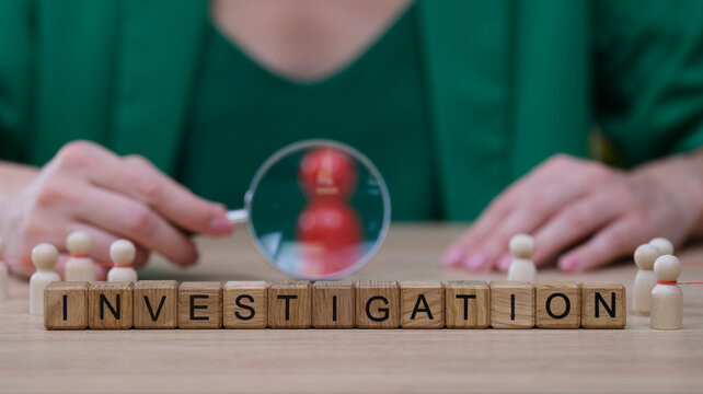 Hands hover over wooden blocks spelling investigation, while a magnifying glass amplifies attention on a figurine. Curious minds are at work in this creative setting.