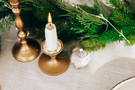 Candle on a table with greenery and small Christmas decorative figures during a festive gathering