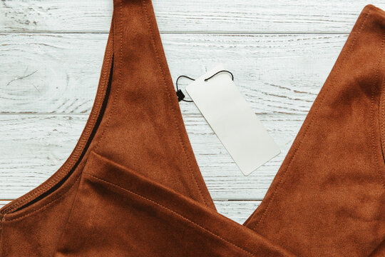 Close up of a brown clothing item with a tag on a wooden surface