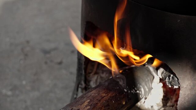 Bright flames burning under a cauldron outdoors. Rustic campfire cooking with glowing firewood and traditional atmosphere