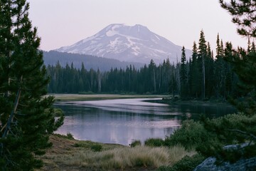 Obraz premium The Mountain Lake Reflected in a Serene Pine Forest and Snowy Peak