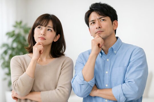 腕を組みながら真剣な表情で悩み事を相談し考え込むカジュアルな服装の若い男女のペア