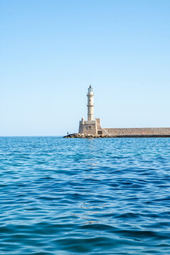 View of the historic Venetian lighthouse at the end of the stone breakwater in the harbor of Chania, Crete, Greece.