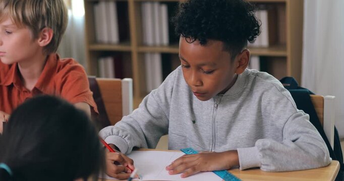 Young Black student drawing precise lines with pencil and ruler during classroom lesson.