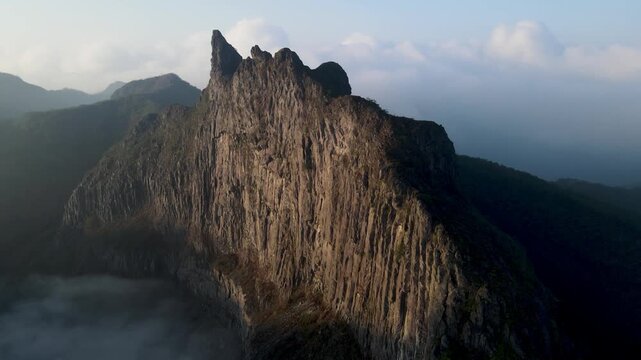 Aerial Drone Footage of Tebing Sumbing on Kelud Mountain Rising Above a Layer of Clouds in East Java, Indonesia. Dramatic Volcanic Cliff and Mountain Landscape Surrounded by Morning Cloudscape.