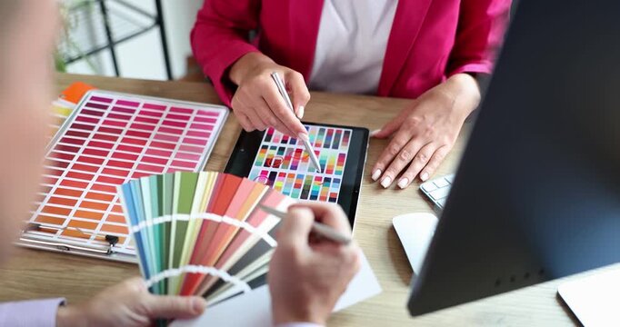 In a bright workspace, enthusiastic designers collaborate over color swatches and digital displays to choose perfect shades for their project. Excitement fills the air as they discuss ideas.