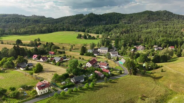 Small village with detached houses along a winding road in a wooded valley