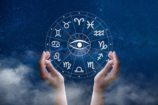 Cupped hands holding an astrology zodiac wheel with all seeing eye, under a starry Milky Way sky.