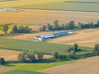Fototapeta premium Farmland aerial view with modern farm building and silos showing agriculture development