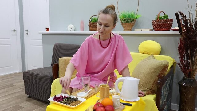 A woman places dried ginkgo biloba leaves in a mug and pours boiling water over them