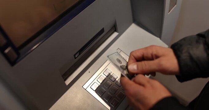 In a bustling urban setting, a person approaches an ATM to withdraw cash. Carefully entering their PIN, they eagerly await their money.