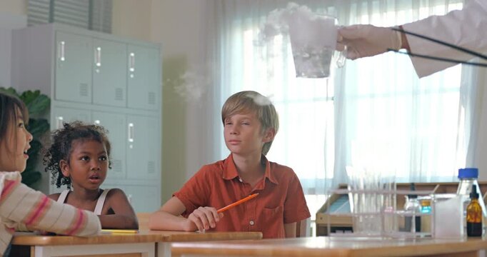 Science teacher demonstrating dry ice experiment with smoking beaker to attentive elementary students in classroom.