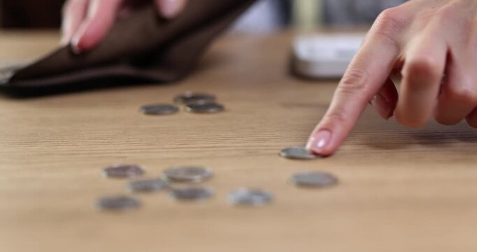 Delicate hands sort and count shiny coins on the warm wooden surface. Each coin gleams as the light catches its curves, creating a sense of calm focus in the air.