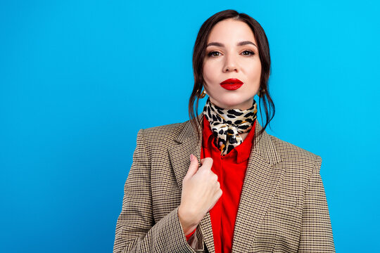 Confident fashion portrait of a woman wearing a checked blazer, red blouse and leopard scarf against a bright blue background