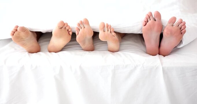 A delightful morning unfolds as cheerful feet peek out from under soft blankets. The warm sunlight fills the cozy bedroom, creating a peaceful atmosphere perfect for a fun gathering.