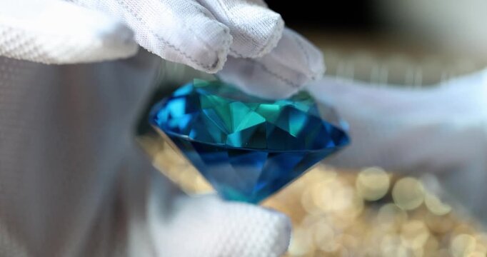 In a bright, elegant setting, a person carefully holds a stunning blue diamond, showcasing its brilliant facets and dazzling reflections.
