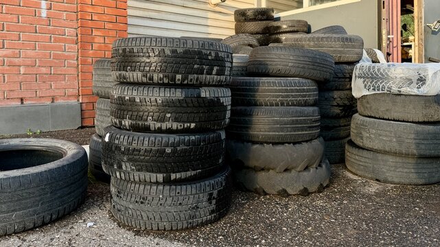 Stacks of used and seasonal car tires stored outside an automotive repair workshop.