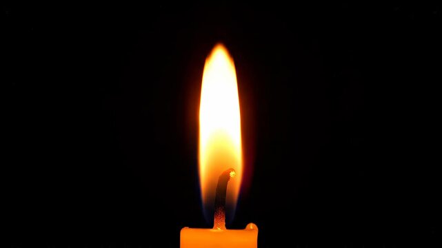 Single candle flame flickering gently in darkness with subtle focus pull and warm glow for atmospheric background