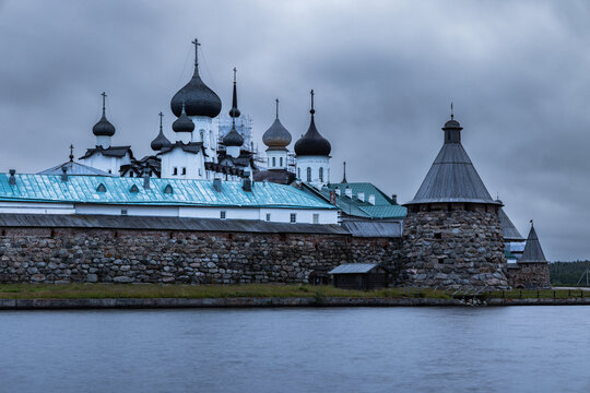 View of Solovetsky Monastery with its historic stone walls, onion domes, and turquoise roofs under a cloudy sky in Solovetsky, Arkhangelsk Oblast, Russia.