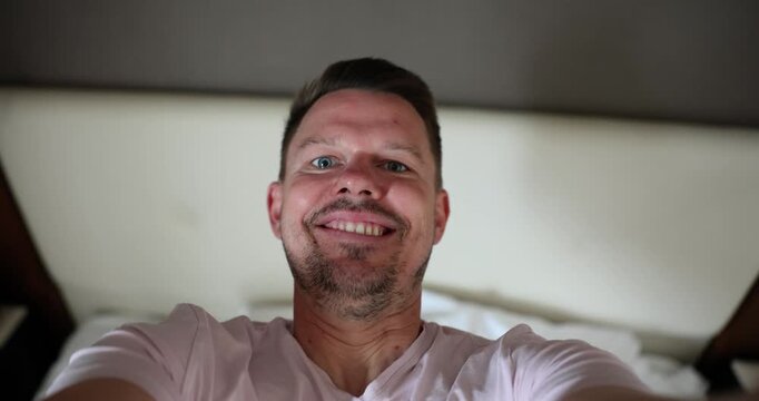 Bright sunlight spills into a cheerful bedroom as a man takes playful selfies from different angles. His wide smile and relaxed vibe bring warmth to the morning moments.