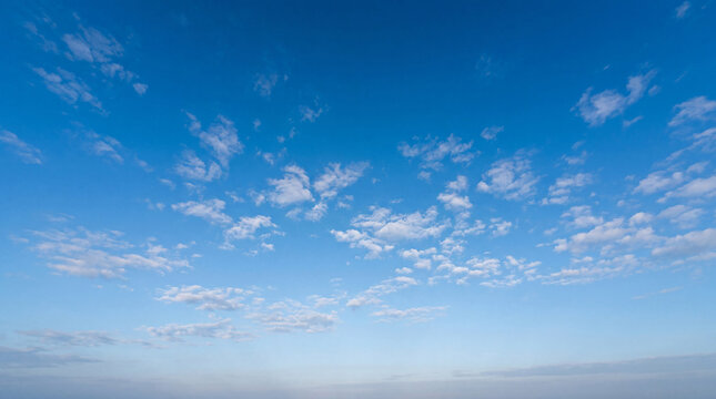 Vast clear blue sky with widely scattered small cumulus clouds, creating a clean, airy, and expansive atmosphere.