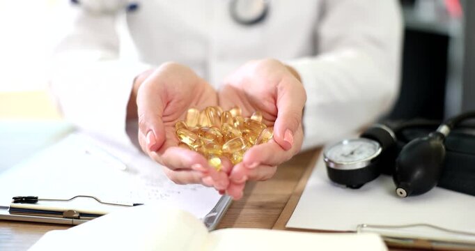 In a bright clinic atmosphere, a healthcare professional holds a generous handful of golden capsules, showcasing their importance for health.